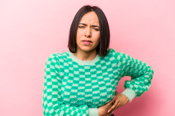 Young hispanic woman isolated on pink background having a liver pain, stomach ache.