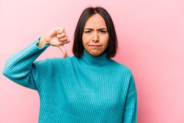 Young hispanic woman isolated on pink background showing thumb down and expressing dislike.