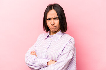 Young hispanic woman isolated on pink background frowning face in displeasure, keeps arms folded.