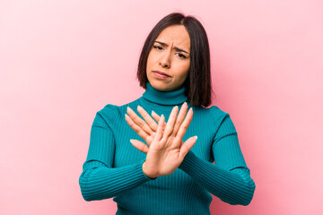 Young hispanic woman isolated on pink background doing a denial gesture