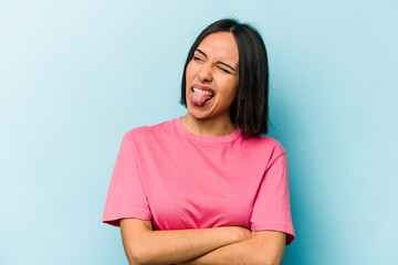 Obraz premium Young hispanic woman isolated on blue background funny and friendly sticking out tongue.