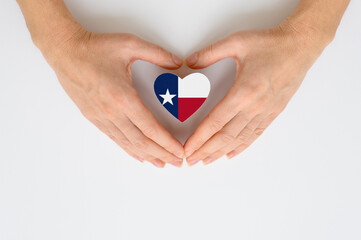 Texas state flag in the shape of a heart in female hands