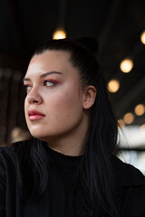 Close up photo of young beautiful woman. Bokeh lights at back. Black background.