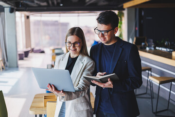 Beautiful european business woman and business man looking at the screen of a laptop computer and talking to a businessman in the office.