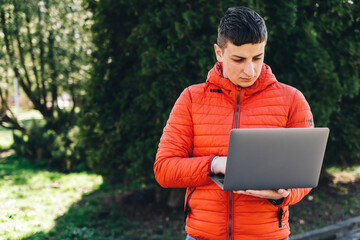 Portrait of smiling student holding book and laptop looking at camera standing in university campus