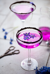 selective focus pink gin cocktails with chocolate decoration and spring flowers on the tile table with scissors rustic light style