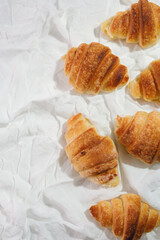 homemade croissants on a white textile background.