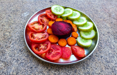 Stock photo of classic healthy and colorful salad plate with tomato, beetroot, cucumber and carrot, kept on table under nature light. Picture captured at Bangalore, Karnataka, India.