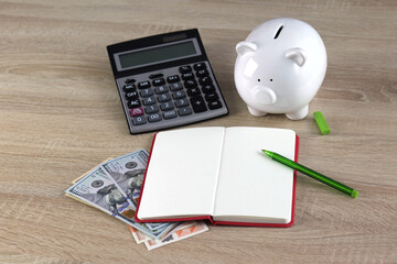 A piggy bank and a calculator sitting on a wooden background, Calculating your expenses
