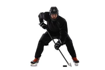 Male hockey player with the stick on ice court and white background. Active training