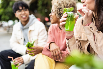 Happy young friends drinking cocktails outdoors - Multiracial people social gathering together while toasting alcohol drink in city street
