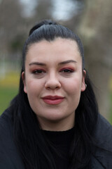 Portrait of beautiful girl at outside. Green background. She is smiling. Close up photo.