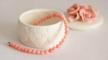 Pink coral bracelet and porcelain jewelry box isolated on white background, on table.	