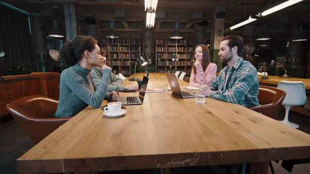 Group of diverse young colleagues discuss plans at conference table
