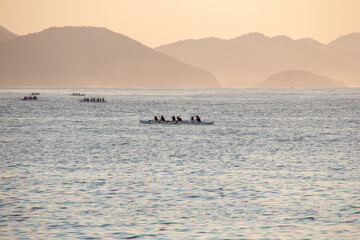 Obraz premium silhouette of people paddling a hawaiian canoe at Copacabana Beach in Rio de Janeiro.