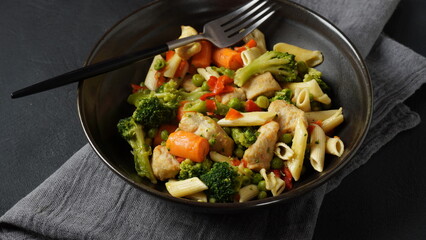 Pasta salad with baked vegetables and fried pieces of chicken breast