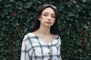 Naklejka premium Girl on the background of a green wall. Portrait of a beautiful young girl.
