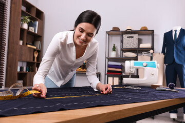 Dressmaker with measuring tape working in atelier