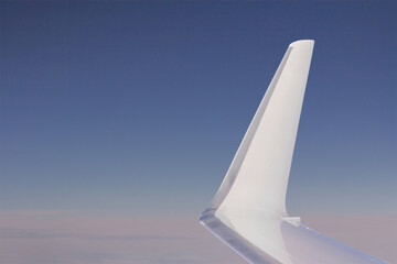 An airplane wing on a defocus background of sky and clouds.