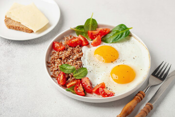 Eggs, buckwheat, tomatoes and spinach on a plate. Healthy breakfast.