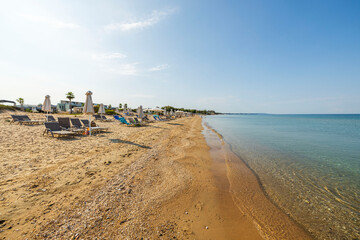 Beautiful view of beach with sun loungers and umbrellas against backdrop of sea. Greece. 