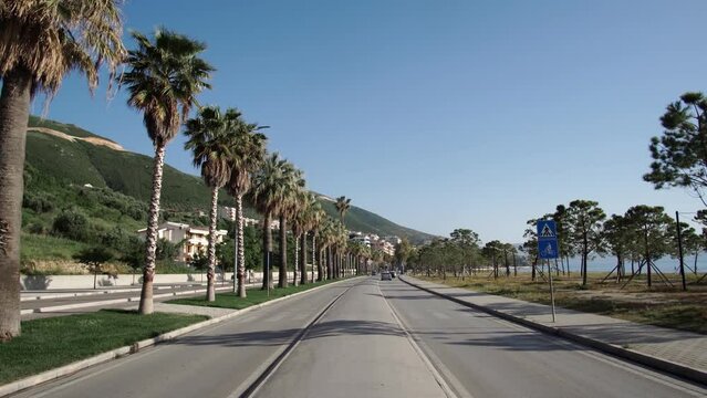 View of the boulevard road among the palm trees and the sea in Vlore, Albania