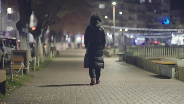 Curly hair hispanic lonely woman walk in city at night, slow motion, cinematic dof