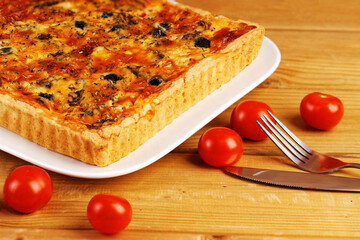 Homemade cheesy Quiche with tomatoes, champignons and olives. Closeup view.
