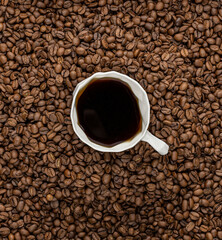 A white cup of black coffee in a mountain of coffee beans