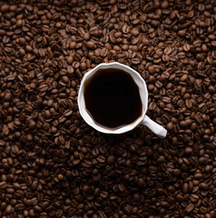 A white cup of black coffee in a mountain of coffee beans