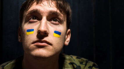 Crying man with national flags of Ukraine on his cheeks