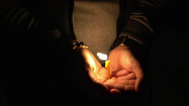 Woman holding lighted burning candle in her hands on Easter at midnight, as Ortodox sign and symbol of Christian faith