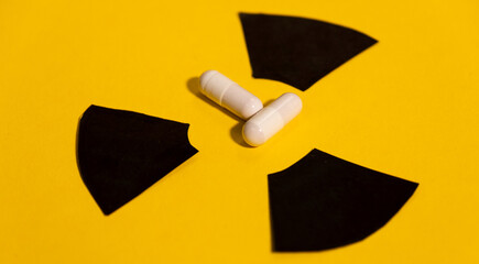 Two anti-radiation pills based on pottasium iodine on a yellow background and the radiation warning...