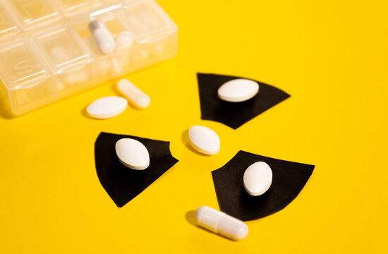 Multiple anti-radiation pills based on iodine on a yellow background and the radiation warning sign