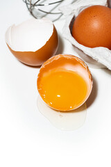 broken chicken egg on white background, baking ingredients, vertical top view