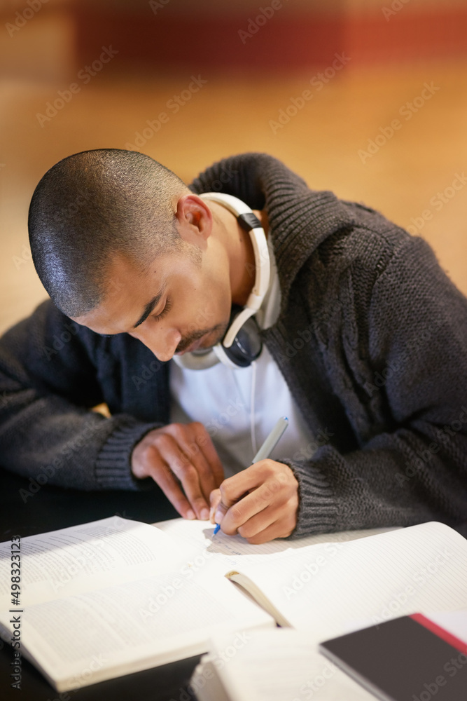 Poster working hard on his latest assignment. cropped shot of a college student working at campus.