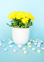 Easter card. Easter porcelain bunny, painted eggs and a yellow flower in a white pot on a blue background. Yellow-blue concept.
