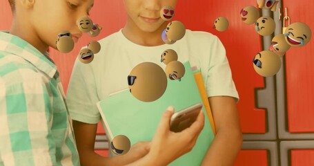 Animation of emojis icons over diverse schoolboys using smartphone