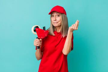 senior gray hair woman making capice or money gesture, telling you to pay. packer employee concept