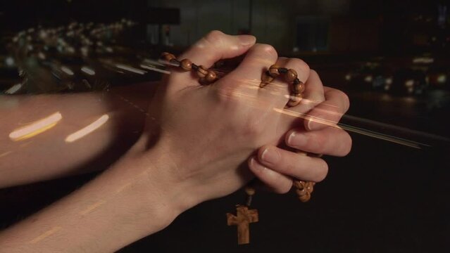 Animation of hands of caucasian woman holding rosary and praying over road traffic