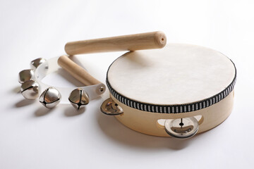 Wooden tambourine, rhythm stick and hand bells on white background. Montessori musical toy - obrazy, fototapety, plakaty