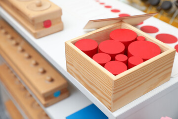 Set of wooden geometrical objects and other montessori toys on shelves, closeup - obrazy, fototapety, plakaty