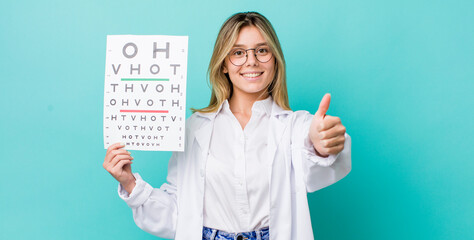 pretty blonde woman feeling proud,smiling positively with thumbs up. optical vision test concept