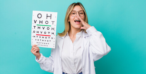 pretty blonde woman feeling happy,giving a big shout out with hands next to mouth. optical vision test concept