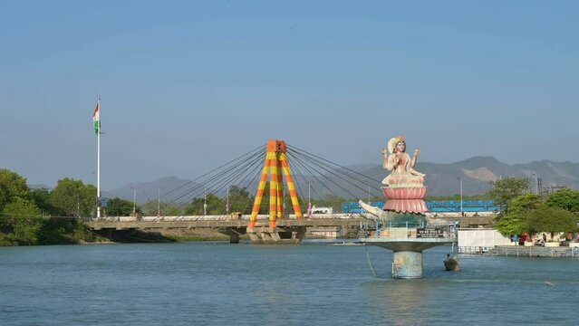 Haridwar, Uttarakhand, India - 10th April 2021 : View of Haridwar bridge over river Ganges, Har Ki Pauri Ghat on the banks of Holy river Ganges, with blue sky and Himalayan mountains in background.