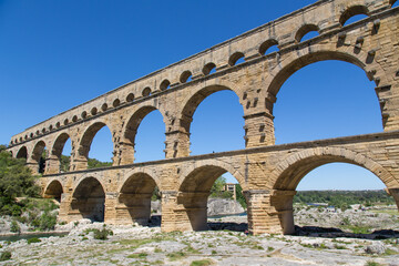Fototapeta na wymiar Famous Pont du Gard - an iconic Ancient Roman bridge, aqueduct and engineering masterpiece in the region Provence, France. It is formed by three floors of arcades, massive arches and pillars