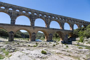 Papier Peint photo autocollant Pont du Gard Famous Pont du Gard - an iconic Ancient Roman bridge, aqueduct and engineering masterpiece in the region Provence, France. It is formed by three floors of arcades, massive arches and pillars