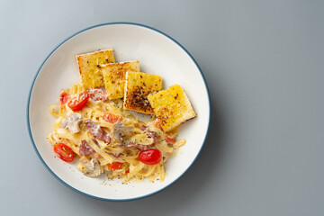 homemade fettuccine pasta with white cream sauce and garlic bread. fettuccine Carbonara made with eggs, hard cheese, cured pork, and black pepper. Italian food.