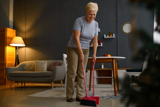 Aged Mature Woman Sweeping Floor At Home