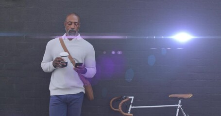 Animation of light spots over african american man using smartphone